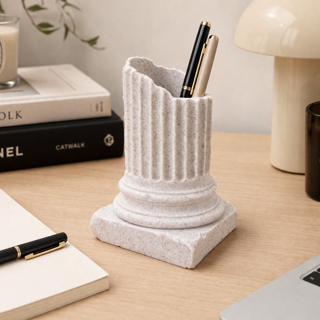 Decorative pen holder on a desk with books, candles, and a laptop.