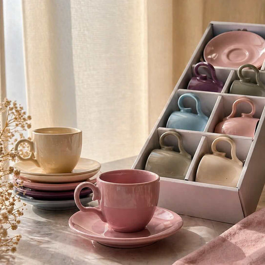 Set of ceramic cups and saucers on a table with a box of additional items in the background.