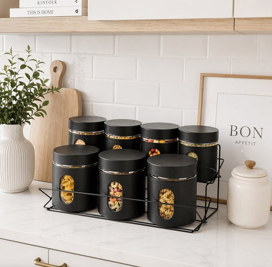 Set of black storage jars with gold accents on a kitchen counter.