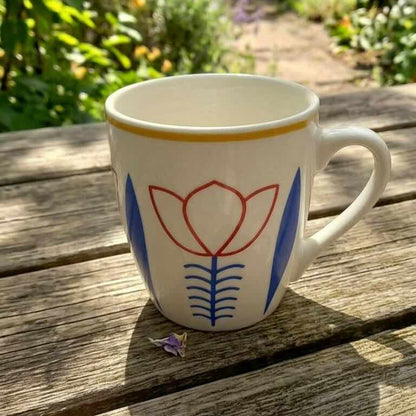 Mug with floral design on a wooden table outdoors