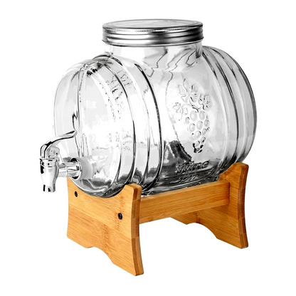 Clear ribbed glass beverage dispenser with a metal lid and spout, displayed on a light wood stand against a white background.
