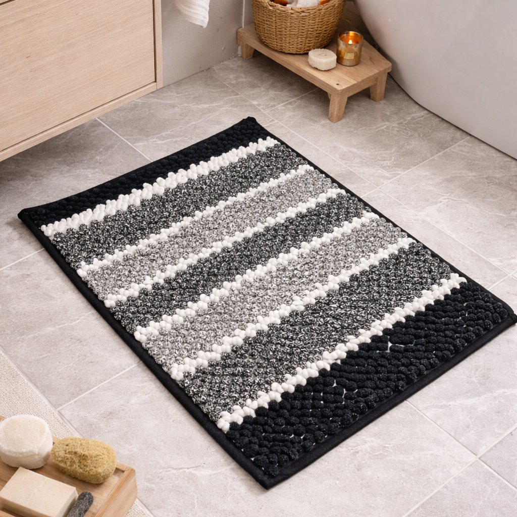 Black and white striped bath mat on a bathroom floor with a bathtub and shelves in the background.