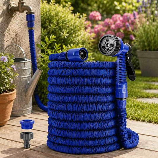 Blue expandable garden hose with spray nozzle on a wooden deck with plants and flowers in the background.