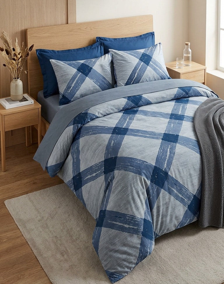 Blue and gray plaid comforter set on a bed in a bedroom with wooden headboard and side tables.