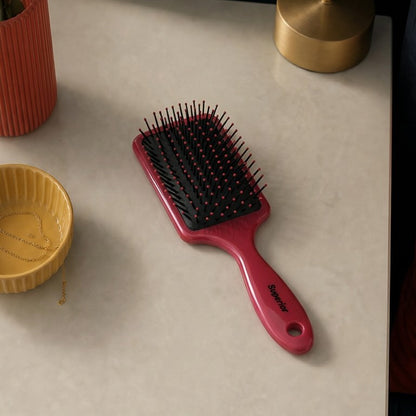 Red hairbrush on a marble surface with decorative elements.