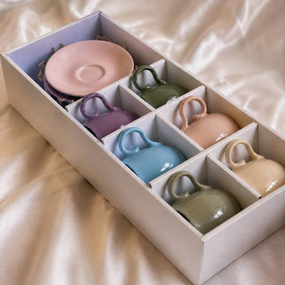 Set of colorful ceramic cups and saucers in a box on a beige fabric background