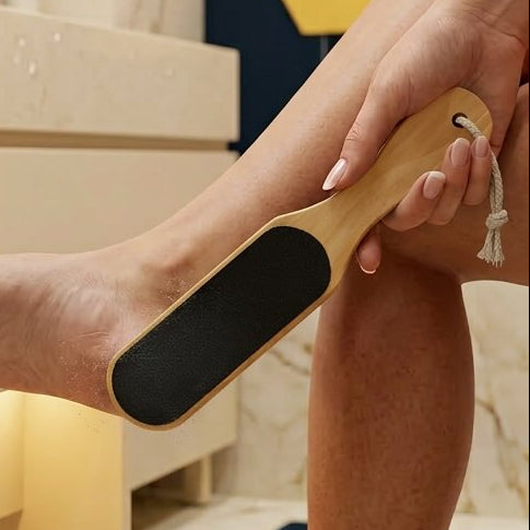 Person using a pumice stone on their foot in a bathroom setting.