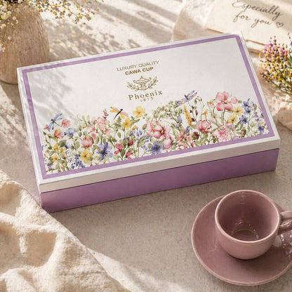Cana Cup Phoenix tea box with floral design on a table with a pink cup and saucer.