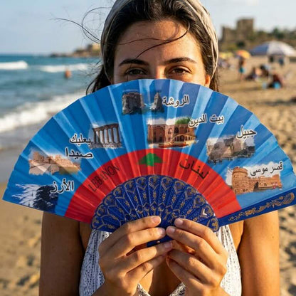 Woman holding a colorful fan with images on a beach