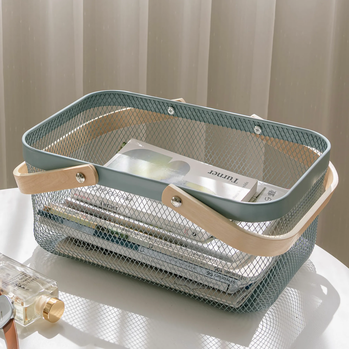 Mesh storage basket with wooden handle on a white surface
