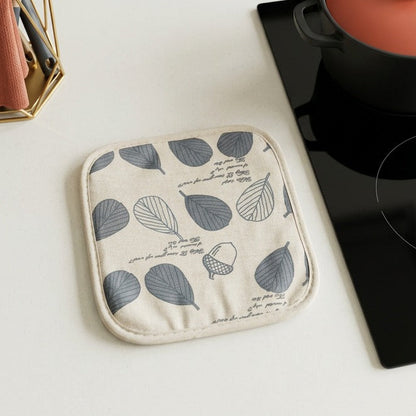 Kitchen scene with a pot holder on a white countertop next to a pot and utensils.