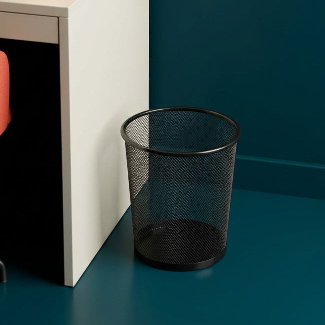 Modern office setup with a desk, lamp, chair, and trash can against a dark blue wall.