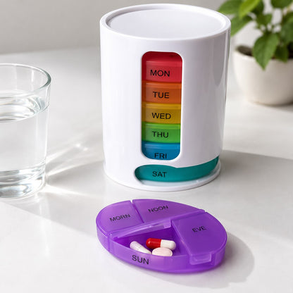 A white weekly planner cup or organizer with colorful day tabs labeled SUN through MON, standing on a light marble countertop in a softly blurred kitchen setting.
