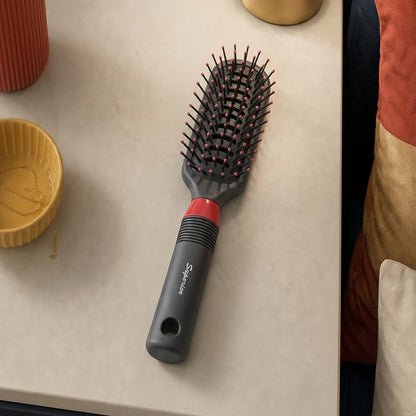 Hairbrush on a table next to a small plant and lamp