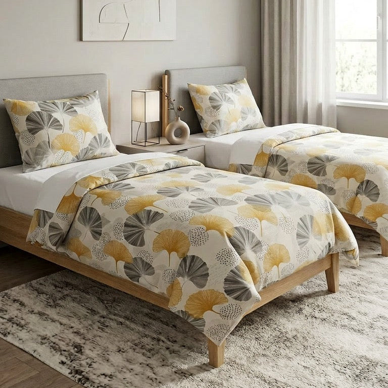 Neatly made bed with a patterned comforter in a bright bedroom.